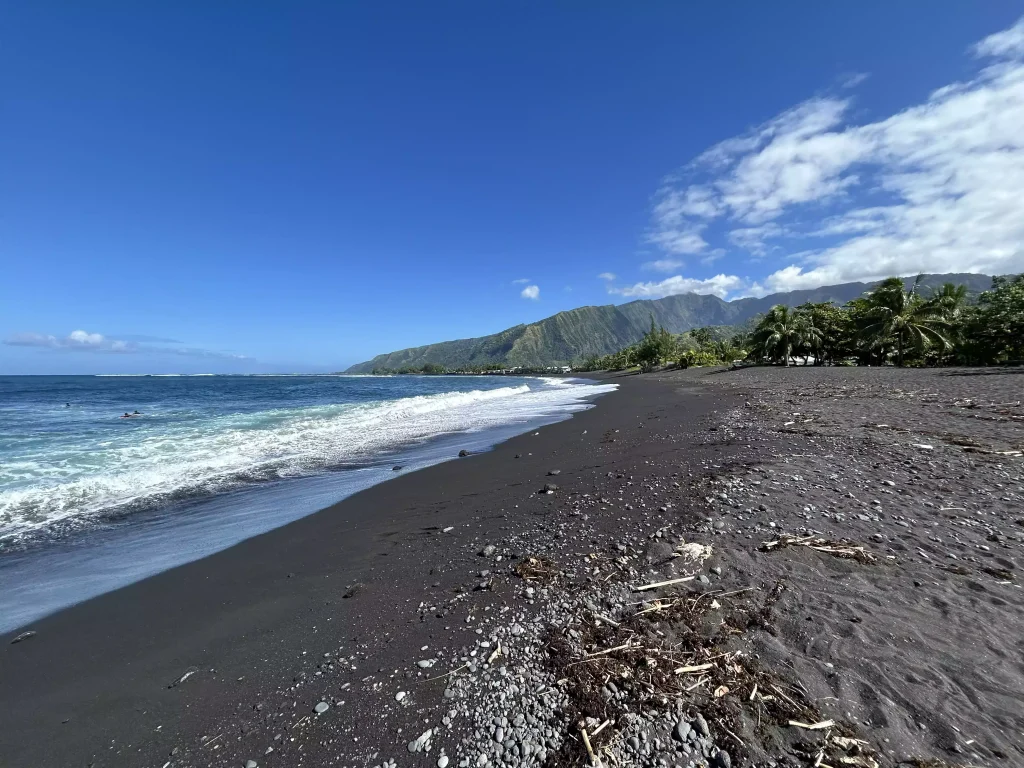 Surfeurs à l'eau sur la plage de sable noir de Papara, à Tahiti